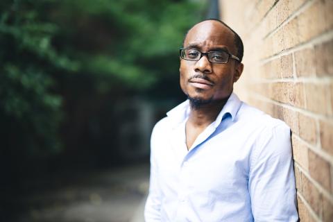 Joseph Williams poses for a photo leaning against a brick wall.
